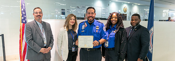 Hector at TSA checkpoint holding certificate with colleagues