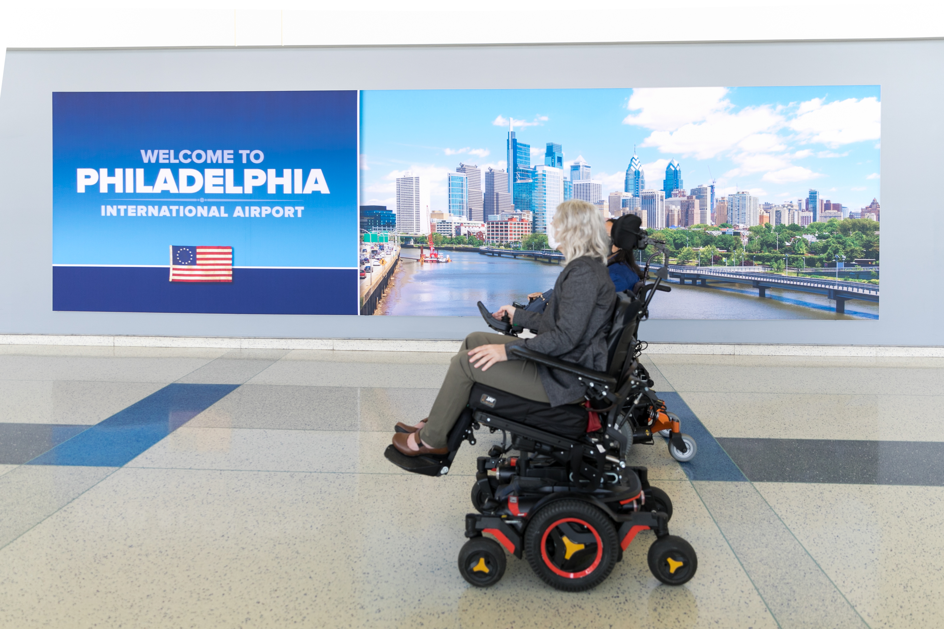 person in wheelchair in front of PHL sign