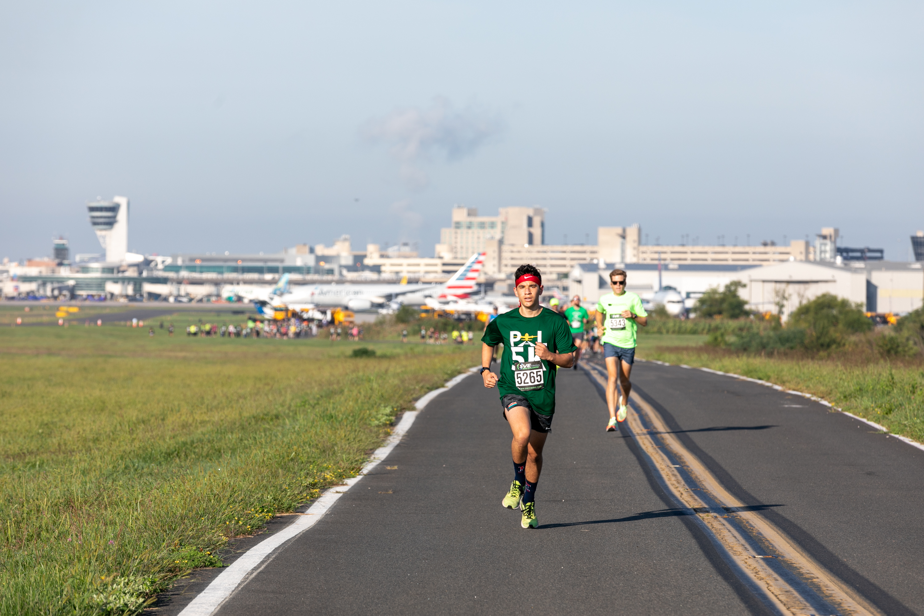 Participants running on runway with planes in background